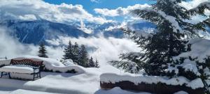 un banco cubierto de nieve con vistas a las montañas en Chalet La Louise avec vue imprenable, en Crans-Montana