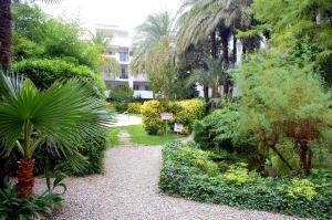 un jardín con palmeras y un paseo. en Global Immo 3369 ROYALE MARINE I Xaloc 1-2, en Roses