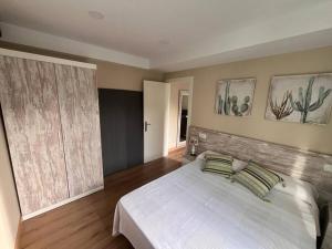 um quarto com uma grande cama branca e 2 almofadas em Casa Bolingas - Apto 5 em Comillas