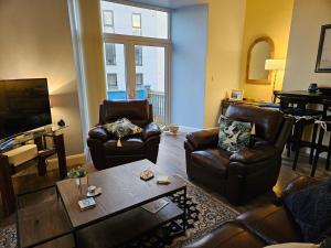 a living room with leather furniture and a flat screen tv at Atlantic Views ground floor apartment in Portrush