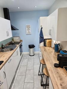 cocina con armarios blancos y encimera de madera en Atlantic Views ground floor apartment en Portrush