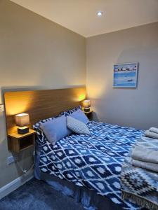 a bedroom with a bed with a blue comforter and two lamps at Atlantic Views ground floor apartment in Portrush