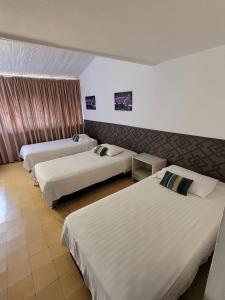 um quarto de hotel com três camas em Hotel Gimaura em Ríohacha