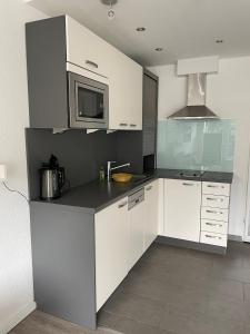 une cuisine avec des armoires blanches et un micro-ondes dans l'établissement Haus am Park Sünnig Utsicht, à Norderney