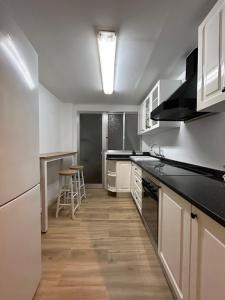 a kitchen with white cabinets and a black counter top at Frente al puerto y junto a la playa del Arenal in Burriana