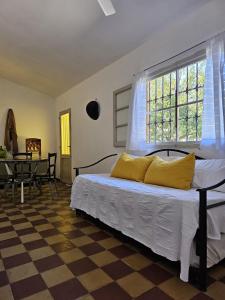 um quarto com uma cama com almofadas amarelas em Casa Regino em Villa Cura Brochero