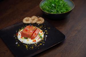 a black plate with food on a wooden table at Mammoth Lodge by Alpine Residences in Courchevel