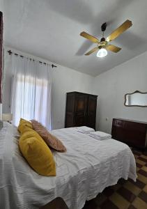 een slaapkamer met een bed met gele kussens en een plafondventilator bij Casa Regino in Villa Cura Brochero