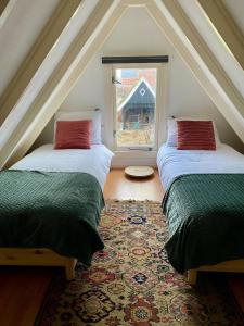 2 bedden in een zolderkamer met een raam bij LooSan Lodges Gastenhuis in Reutum