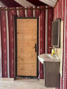 een badkamer met een wastafel en een houten deur bij Lucas Camp Wadi Rum in Wadi Rum