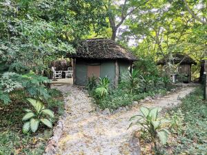 a small shack with a grass roof in a garden at Bamba Kofi Tented Camp in Watamu