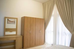 a bedroom with a wooden cabinet and a window at Your Silicon Oasis Escape-1bhk in Dubai +7 photos
