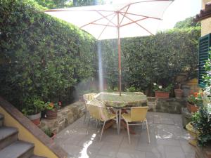 uma mesa e cadeiras com um guarda-sol num jardim em Villino ida em Follonica