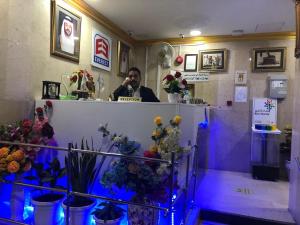 a man talking on a cell phone in a room with flowers at Everest Hotel Apartments in Sharjah
