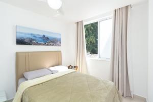 een slaapkamer met een bed en een groot raam bij Luxo em Ipanema 304 in Rio de Janeiro