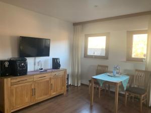 ein Wohnzimmer mit einem Tisch und einem Flachbild-TV in der Unterkunft Ferienwohnung in Oberems