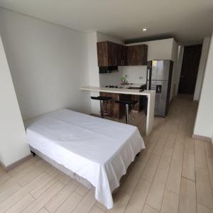 1 dormitorio con 1 cama blanca y cocina en Miraflores, en Cali