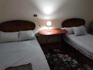 Cette chambre comprend deux lits et une table avec une lampe. dans l'établissement Dokki private home with 2 rooms WiFi Air-conditioning, au Caire