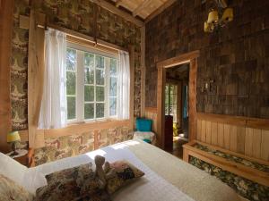 Un dormitorio con una cama grande y una ventana en La Casita del Bosque, en Castro