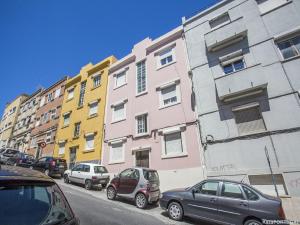 eine Reihe von Gebäuden auf einer Straße mit geparkten Autos in der Unterkunft Calado Apartments in Lissabon