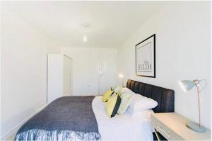 1 dormitorio con 1 cama con sábanas blancas y almohadas amarillas en Impeccable 1-Bed Apartment in London en Londres