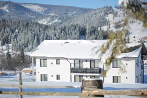 una casa blanca en la nieve con una valla en Vila Dorna Royal, en Şarul Dornei