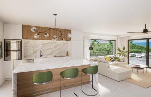 a kitchen with a counter and some green chairs at Aura Anse Marcel in Anse Marcel 