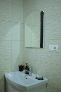 La salle de bains blanche est pourvue d'un lavabo et d'un miroir. dans l'établissement Vila Dorna Royal, à Şarul Dornei