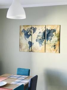 a dining room table with four paintings on the wall at Central Family Apartment in Preveza