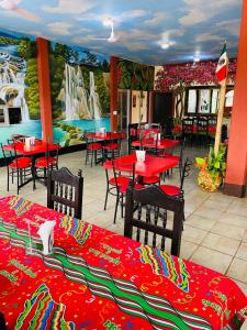 a restaurant with red tables and chairs and a mural at Hotel Del Valle in El Naranjo