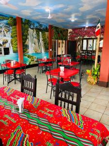 un restaurant avec des tables et des chaises rouges et une fresque murale. dans l'établissement Hotel Del Valle, à El Naranjo