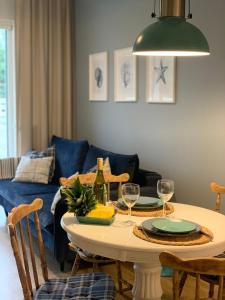 Una sala de estar con una mesa y un sofá azul. en Apartament Hamptons Perłowa Przystań, en Sianożęty