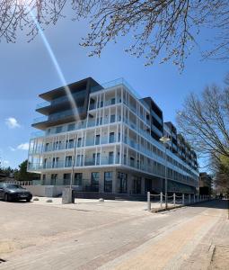 Un gran edificio de cristal con un coche aparcado delante. en Apartament Hamptons Perłowa Przystań, en Sianożęty
