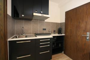 a kitchen with black cabinets and a sink at CHIPPY´S Pension in Vreden