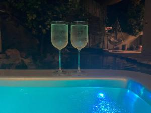 two wine glasses sitting next to a swimming pool at מעיין הגלבוע in Gid‘ona +8 photos