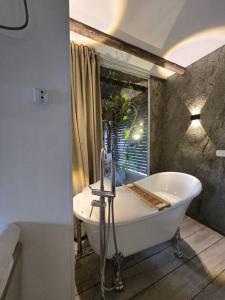 La salle de bains est pourvue d'une baignoire blanche et d'une fenêtre. dans l'établissement מעיין הגלבוע, à Gid‘ona