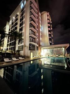 a swimming pool in front of a building at night at Gala City best place gala residence in Kuching