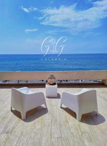 波拉聖喬凡尼的住宿－VILLA G&G CALABRIA，两把坐在海洋前的白色椅子
