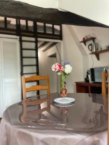 uma mesa de vidro com um vaso com flores em Appartement 1 chambre et Mezzanine em Hargeville