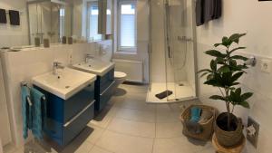 a bathroom with two sinks and a shower and a plant at Kragemann Hotel & Vinothek in Simmerath