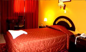 Habitación de hotel con cama y cortinas rojas en Gran Hotel Alturas, en Huaraz