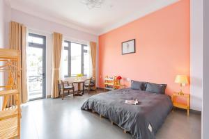 1 dormitorio con pared de color naranja, cama y mesa en Kim Little House Hotel, en Da Lat