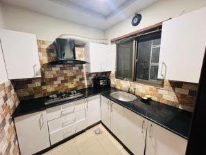 a kitchen with white cabinets and a sink and a window at Stylish & Serene 2BHK Apt in Islamabad