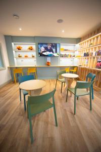 a waiting room with tables and chairs and a tv at Heyday Hostel Ballina in Ballina