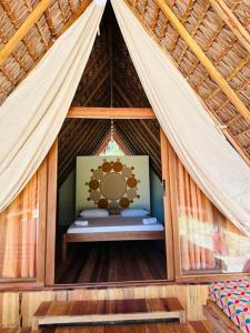 une petite chambre dans une tente au toit de chaume dans l'établissement Emeraude Lodge, à Andilana