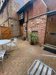 een patio met een tafel en stoelen en een bakstenen gebouw bij Grade II Listed Flint Cottage Sleeps 4 in Norwich