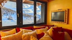 a living room with a couch with pillows and a tv at Hostdomus - 007 Luxury Suites in Sestriere