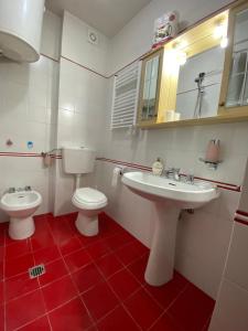 uma casa de banho com 2 lavatórios, um WC e um espelho. em Perla alpina em Abetone