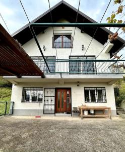 een wit huis met een balkon en een houten tafel bij Dream house near city center in Sarajevo