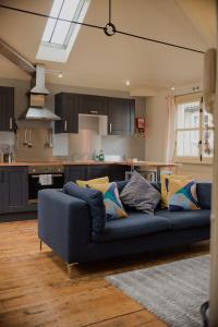 a living room with a blue couch and a kitchen at Studio 2 - Central Location Sleeps 4 in Norwich